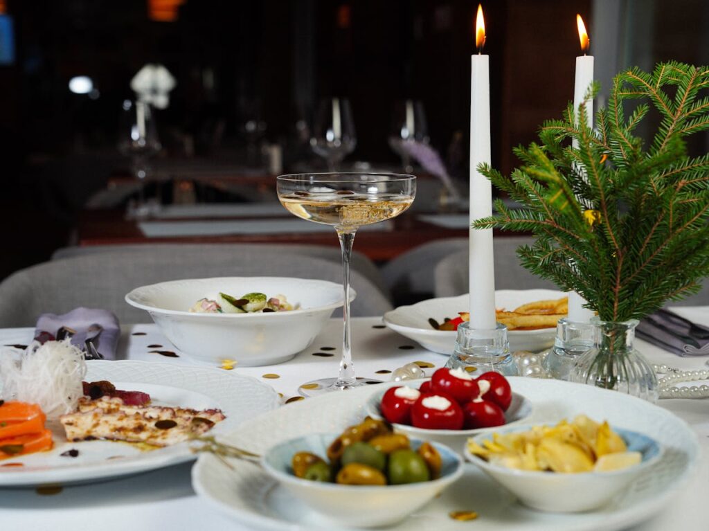 pexels-photo-29616285 A beautifully set dinner table with candles, champagne, and a variety of dishes creating a festive ambiance.